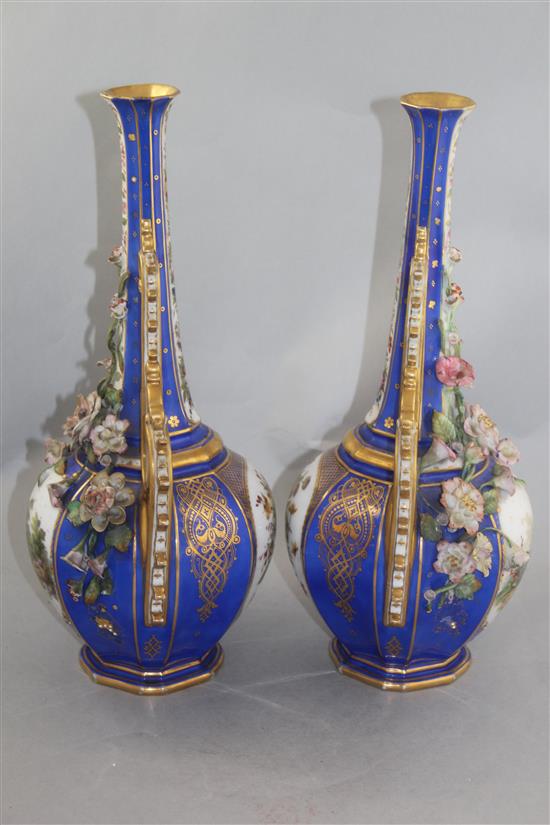 A pair of French jewelled and flower encrusted porcelain bottle vases